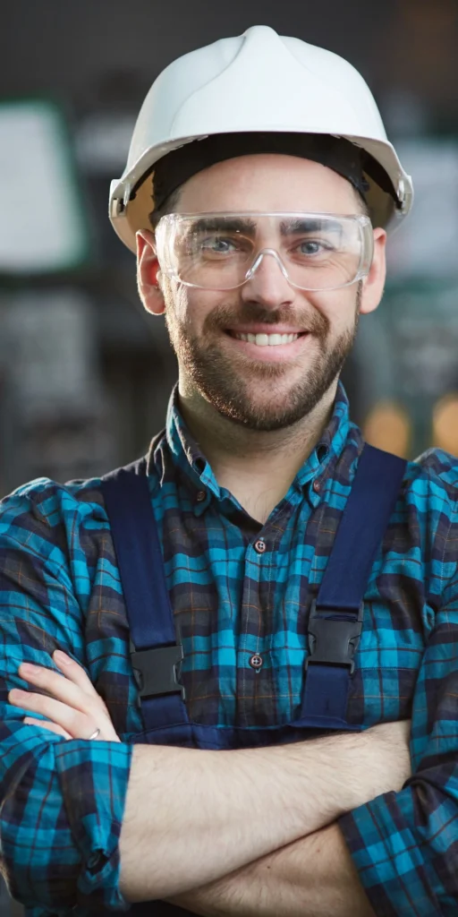 Operator śrutownicy w kasku i okularach.