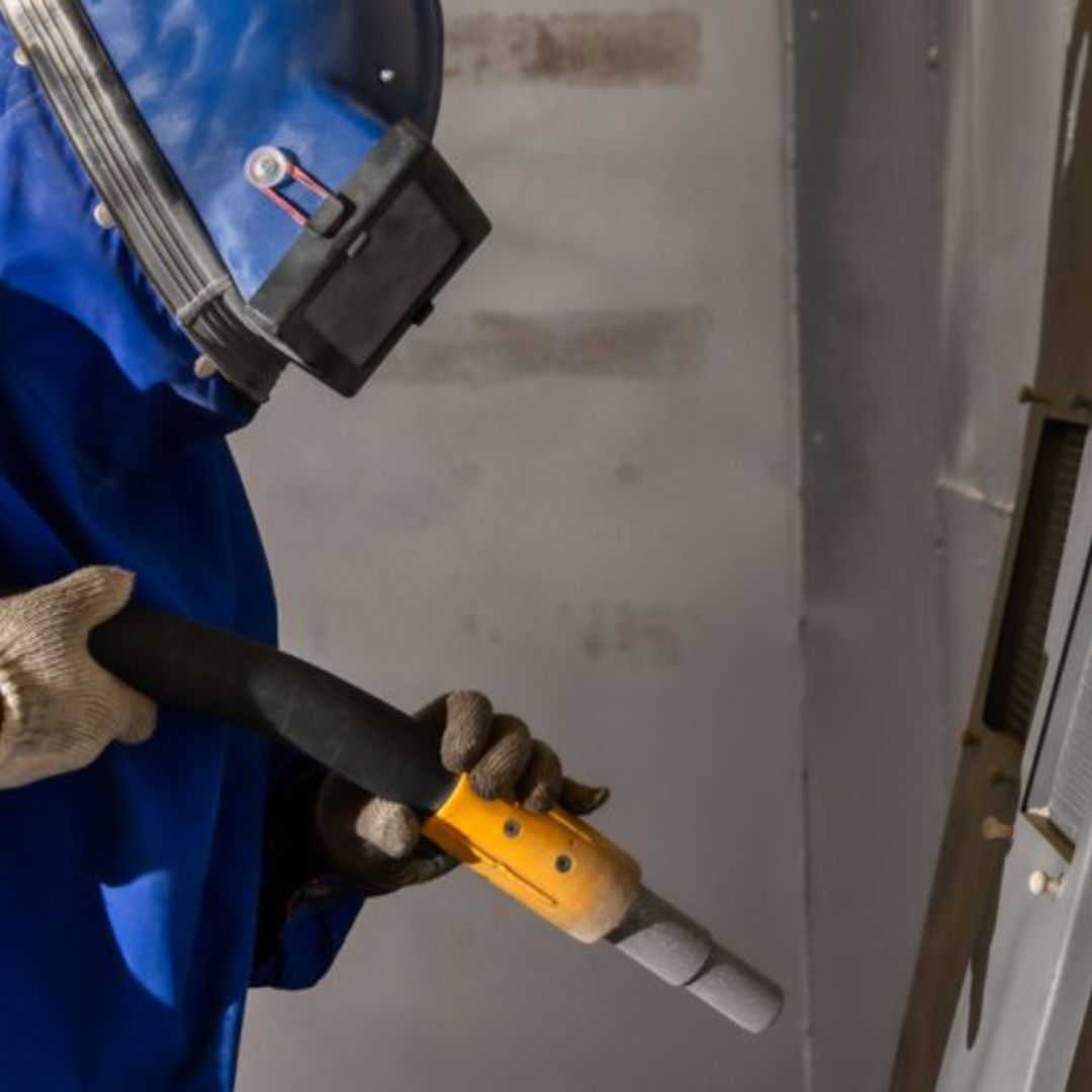 The operator shot-blasts the surface. 