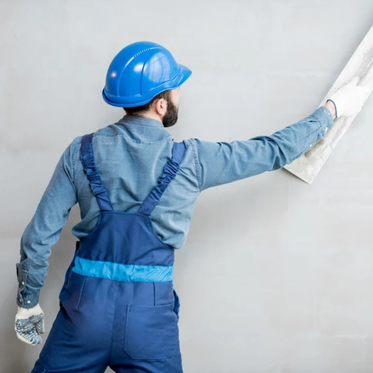 Pracovník omítá stěnu omítkou se skleněnou moučkou. 